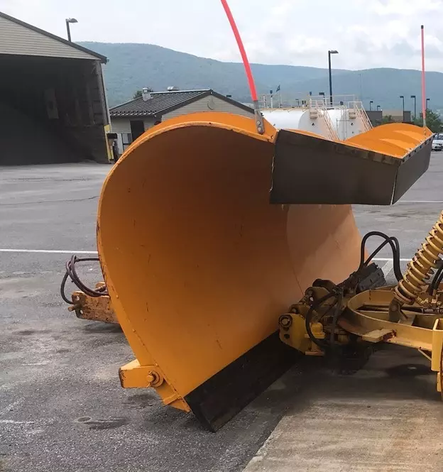 An image showing a large curved yellow plow attached to a PennDOT vehicle.